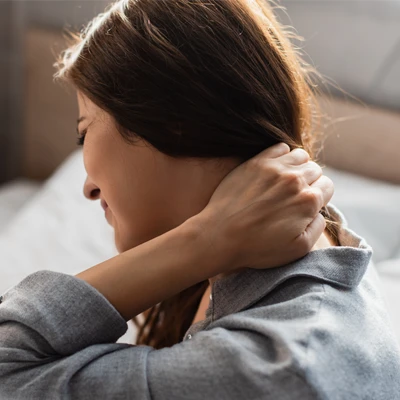 A woman with pain reaching up to hold her neck
